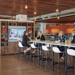 Women drinking coffee at a bar height table with stools